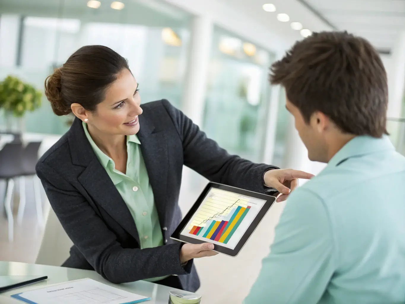 A strategic advisor pointing to a growth chart during a meeting, illustrating how corporate development advisory services can help companies identify opportunities and expand their market presence.